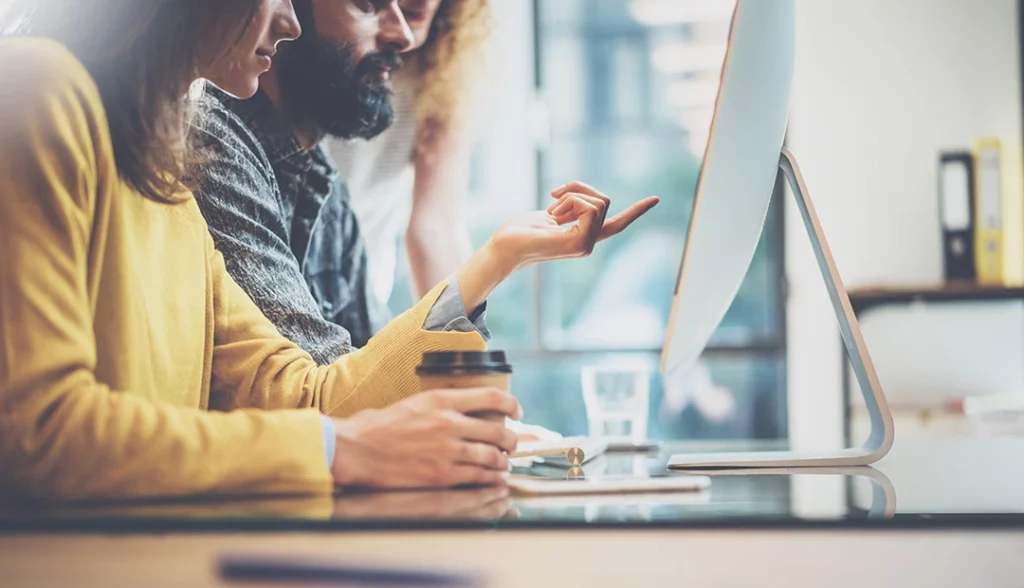 marketer digital com colegas a trabalhar ao computador