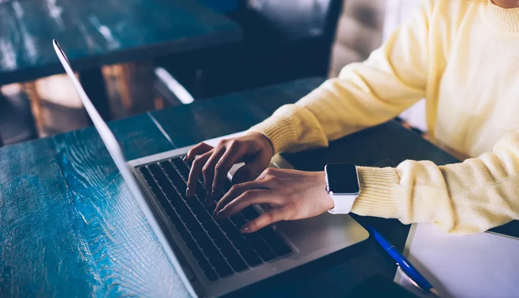 mãos de pessoa ao computador a escrever carta de motivação